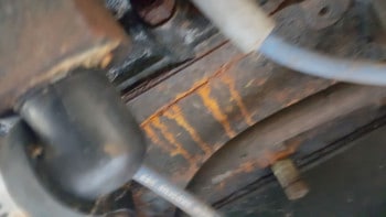A boat engine that has a crack in the block with rust coming out of the crack.