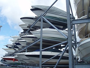 Many boats stored in racks ata boatyard with cloudy skies in the background.