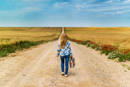 A woman on a country road walking away with a suitcase, referencing the article stating that if the HIN looks altered, to just walk away from the deal.