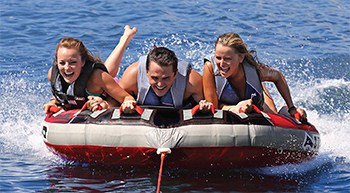 Airhead G-Force 3 person toable tube, being towed in the water with 3 riders.