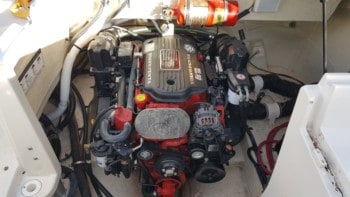 A very clean boat engine and engine bay area where the engine is bright red and the entire engine bay is white.