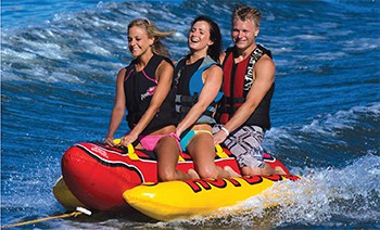 Towable three person Hot Dog Inflateable being towed in the water with three riders.