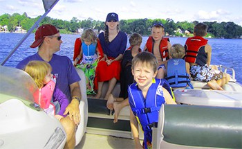 A boat in the water with a husband, wife, and seven children on board and the man enforcing the rules of the boat for safety.