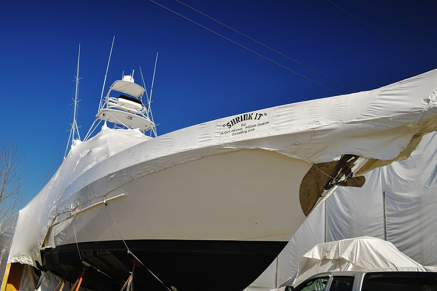 A very large boat to prepare for winter is shrink wrapped to keep the interior safe, and a blue sky in the background.