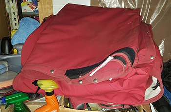 A red boat cover folded up on a shelf in a garage.