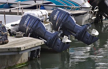 Several outboard boats in a marina floating in the water with the outboards trimmed up and out of the water.