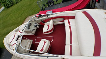 Looking down from above on a maroon and white Bayliner 2050 bowrider on it's trailer in a yard.