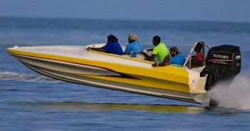 A yellow boat going fast and is above the water with exception to the propeller.