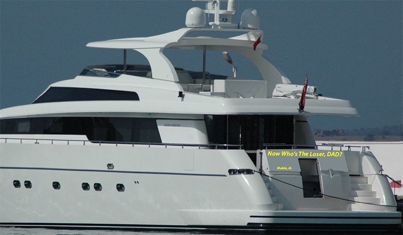 A large white yacht named "Now Who's The Loser DAD?" floating in the wated at dock.
