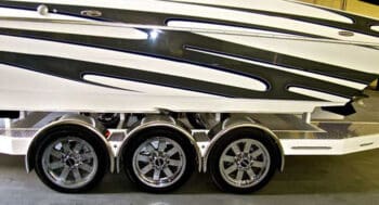 A boat on a trailer that has custom trailer wheels that is on display in a service bay.